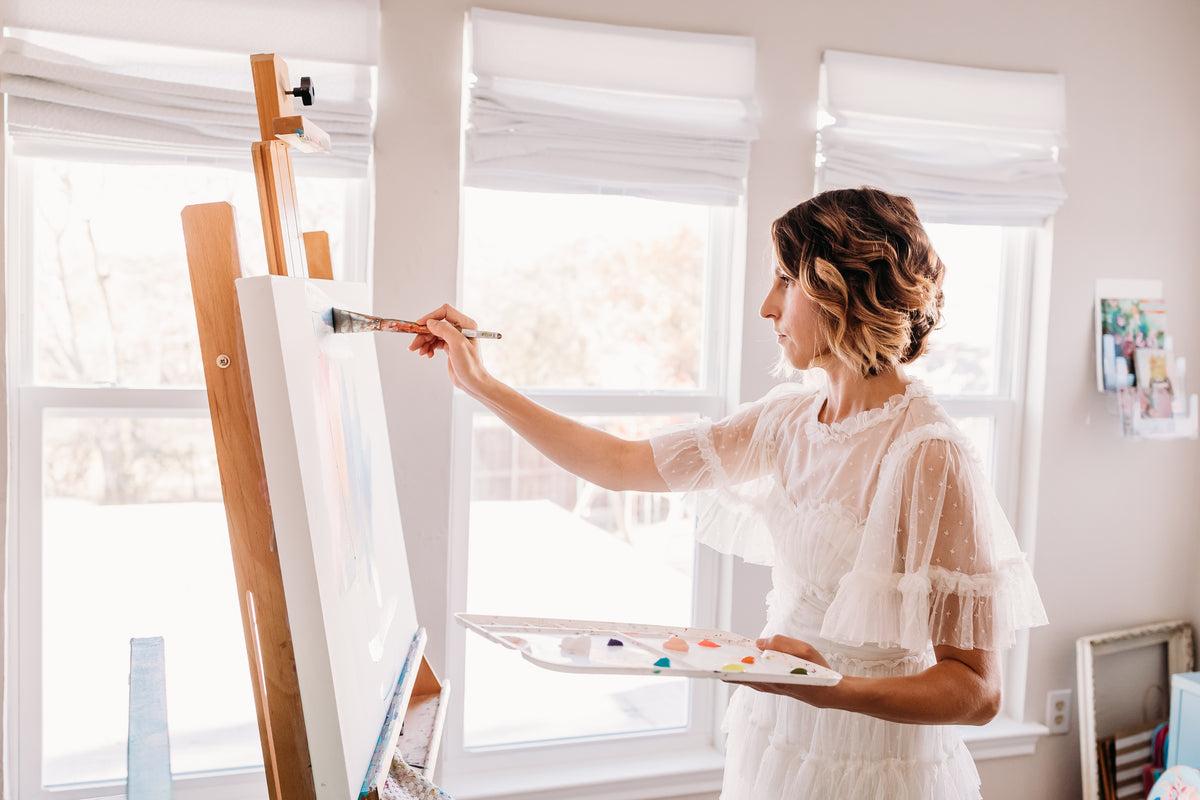 A man standing in front of a painting on a easel.